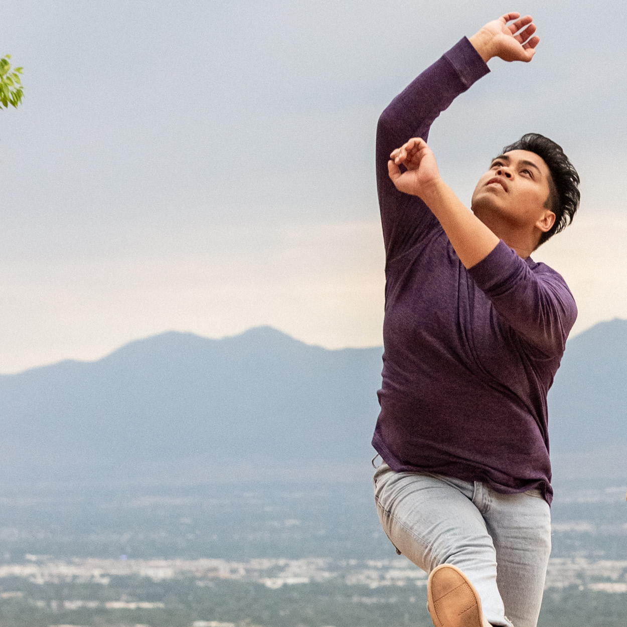 Joshua Yago Mora jumps in a dance outside overlooking the city