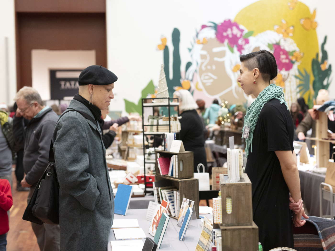 A buyer approaches local artisan Jazmin Gallegos who sells hand-bound books for purchase at the UMFA Holiday Market. Photo by Adelaide H. Ryder.
